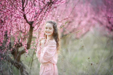 美丽的小女孩在花园里, 反对开花的树木摆在户外
