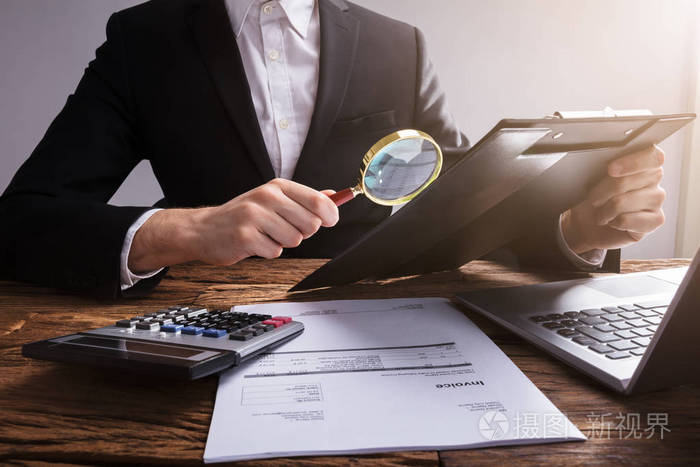 生意人分析文件在剪贴板与放大镜在工作场所木桌上照片 正版商用图片04eccl 摄图新视界