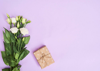 贺卡与春天白色洋花和小礼品盒紫色背景, 空间为您的文本。顶部视图