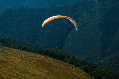 在阳光明媚的夏日，滑翔伞飞过一个山谷