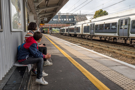 日视图家庭的母亲和两个孩子在英国火车站等火车