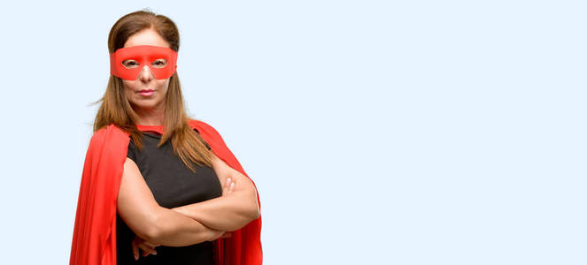 中年超级英雄女子身穿红面具和海角与交叉双臂自信和快乐的大自然微笑笑孤立蓝色背景