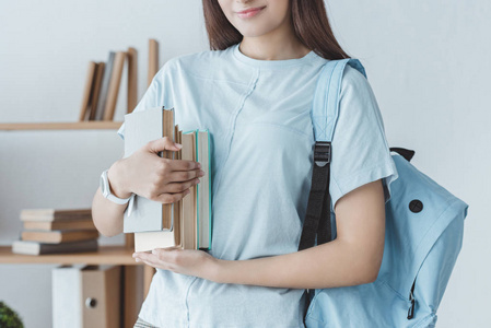 女孩的裁剪视图与背包藏品书