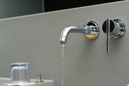 豪华, 设计自来水水龙头与流动的水在银色的墙上。选择性聚焦