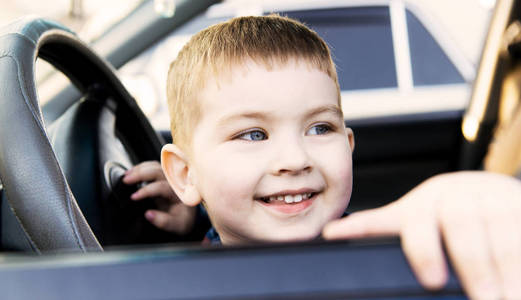 男孩坐在汽车作为司机