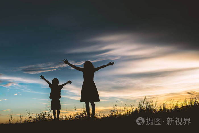 母亲鼓励她的儿子在户外在夕阳下轮廓概念