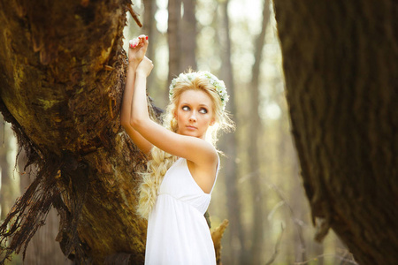 金发女郎站在白色的礼服树上