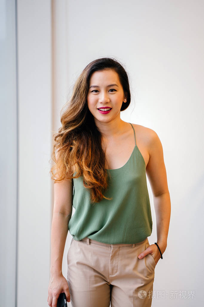 一个迷人的, 年轻的新加坡妇女在她舒适的阁楼公寓的肖像.