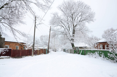 一个质朴的冬季景观与一些老房子和一条宽阔的公路覆盖厚层的积雪