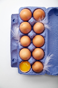 用羽毛装饰的五颜六色的紫罗兰纸板容器中的鸡卵和蛋黄的特写