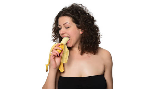 美丽的年轻女人吃香蕉。在白色背景上被隔离