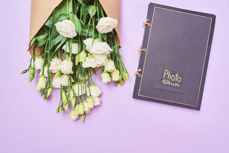贺卡与春天白色洋花和相册在紫色背景, 空间为您的文本。顶部视图
