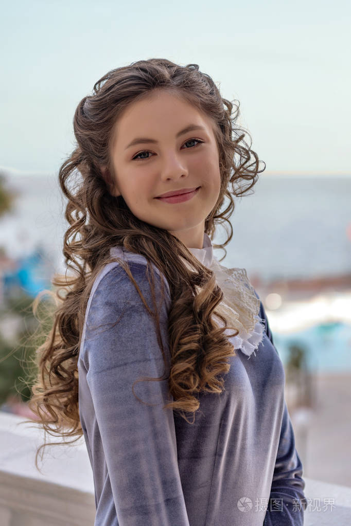 一个微笑狡猾顽皮的女孩的肖像与卷在旧复古礼服