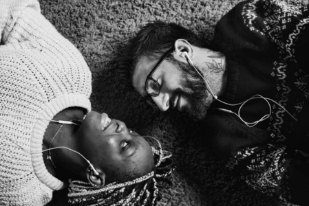 情侣听音乐一起在耳机和躺在地毯上, 黑白相间