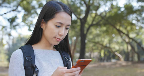 在户外公园使用手机的学生妇女图片