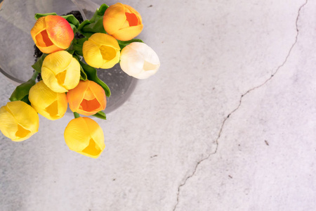郁金香花在玻璃罐子与裂缝白色水泥背景春天概念