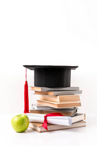 一堆书与学术帽子, 文凭和苹果被隔绝在白色