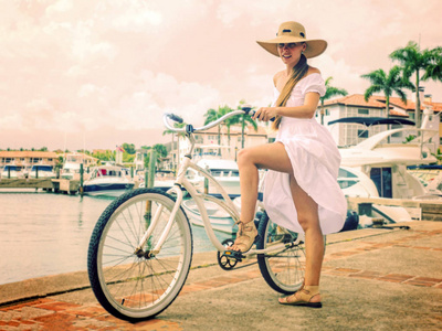 穿白色连衣裙的女孩在海边的自行车上