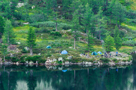 山湖岸边的旅游帐篷。游客在水上的营地