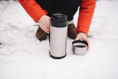 在冬天, 女人的手倒热茶或咖啡出热水瓶