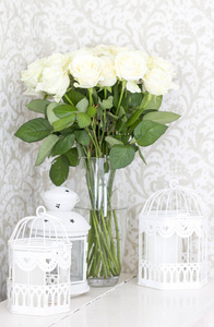 带装饰笼的花瓶里的白玫瑰花束