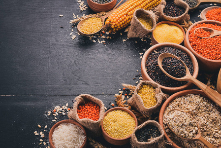 荞麦, 扁豆, 大米, 小米, 大麦, 玉米, 黑米.在黑色的背景.顶部视图.