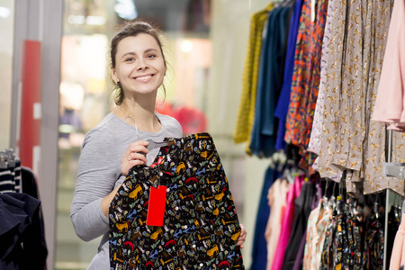 快乐的黑发人在精品店买新衣服.一个在服装店的女孩.妇女购物.