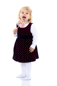 一个小女孩舔糖果棒上