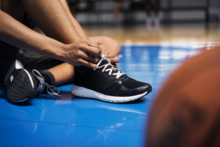 非洲裔美国少年男孩在篮球场上绑鞋带