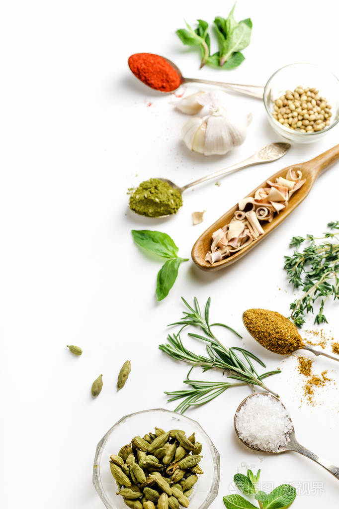 新鲜草本和干五颜六色的香料在勺子和碗安排在一边与拷贝空间