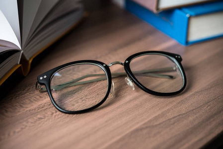 一堆书和眼镜在木桌上。教育理念