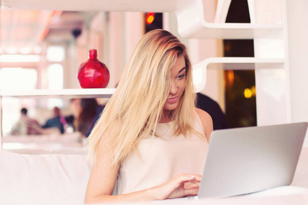 一个漂亮的金发女郎年轻的女商人早上一大早就在咖啡馆里做笔记本电脑。