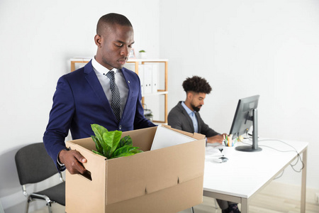 生意人搬出与纸板箱子从办公室与雇员工作在书桌