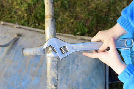 小两岁的男孩手拧螺丝与扳手学习修理手推车在草地户外的顶级视图.