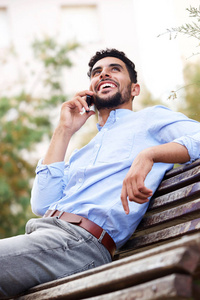 酷年轻的阿拉伯男子肖像在手机上微笑和交谈