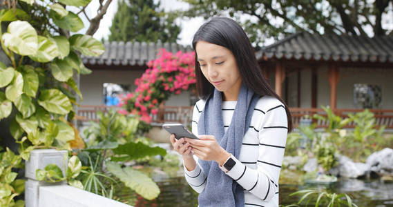 亚洲妇女在中国使用手机, 中国馆花园, 穿冬衣的妇女