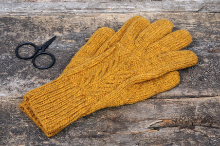 黄手针织手套的木制背景。从上面查看