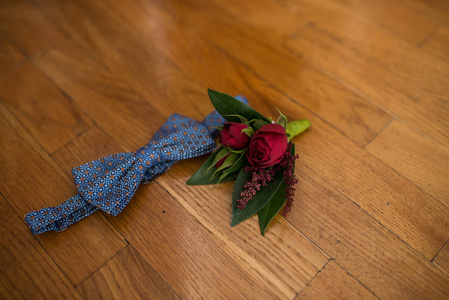 新郎配件 蓝色领带和一个红色的胸花在一个木制的背景。婚礼详情