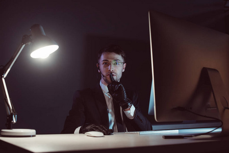 在黑暗中用电脑屏幕显示静默标志的间谍代理肖像