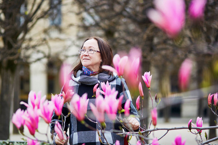 美丽的中年女子在巴黎公园春天天欣赏粉红色白玉兰盛开