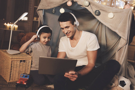 父亲和儿子在家听音乐在手提电脑