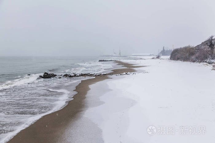 白色蓬松的雪而不是黄色的细沙.海港背景下的雪景