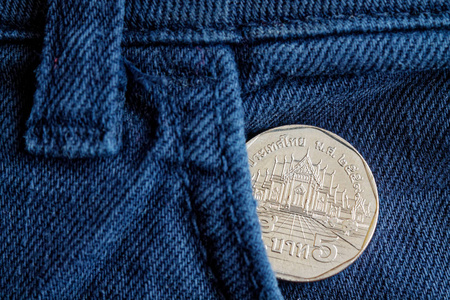 泰国硬币与面值5泰铢在口袋里的老蓝色牛仔牛仔裤
