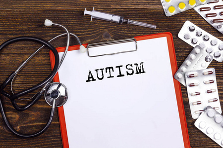 Autisms 用听诊器注射器写在医疗文件夹上的单词
