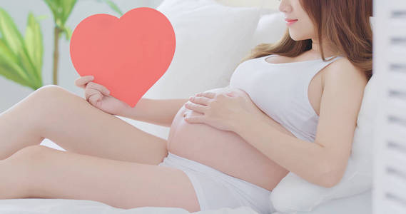 怀孕妇女抱着心脏在床上