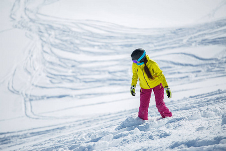 雪山斜坡运动服装滑雪板中黑发戴头盔和面具的照片