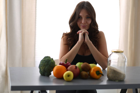 女孩坐在厨房的桌子上的水果和果汁的眼镜