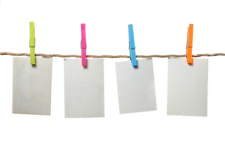 在白色背景上的绳子上挂着的老空白照片照片