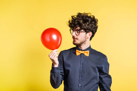 一个年轻男子的肖像与气球在一个黄色的背景工作室