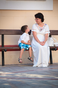 快乐妈妈和儿子坐在长凳上